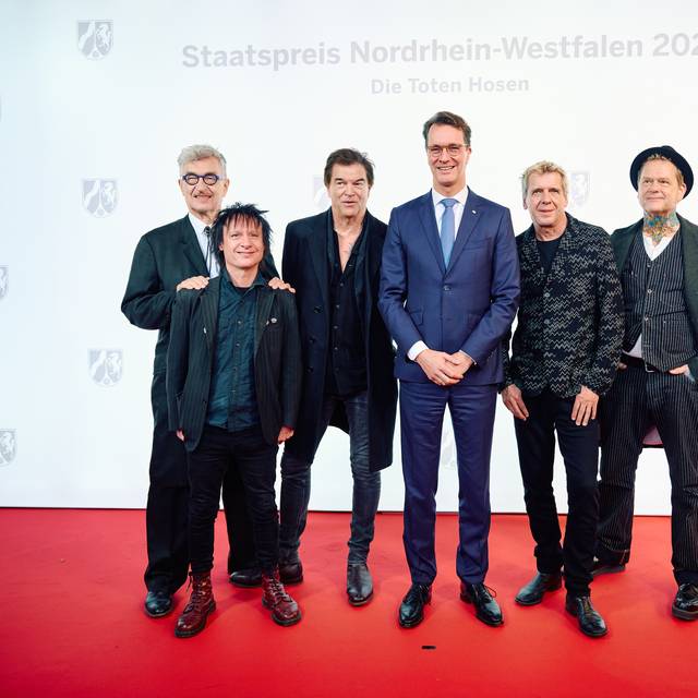 Die Toten Hosen und Ministerpräsident Hendrik Wüst stehen bei der Preisverleihung vom NRW-Staatspreis auf dem Roten Teppich.