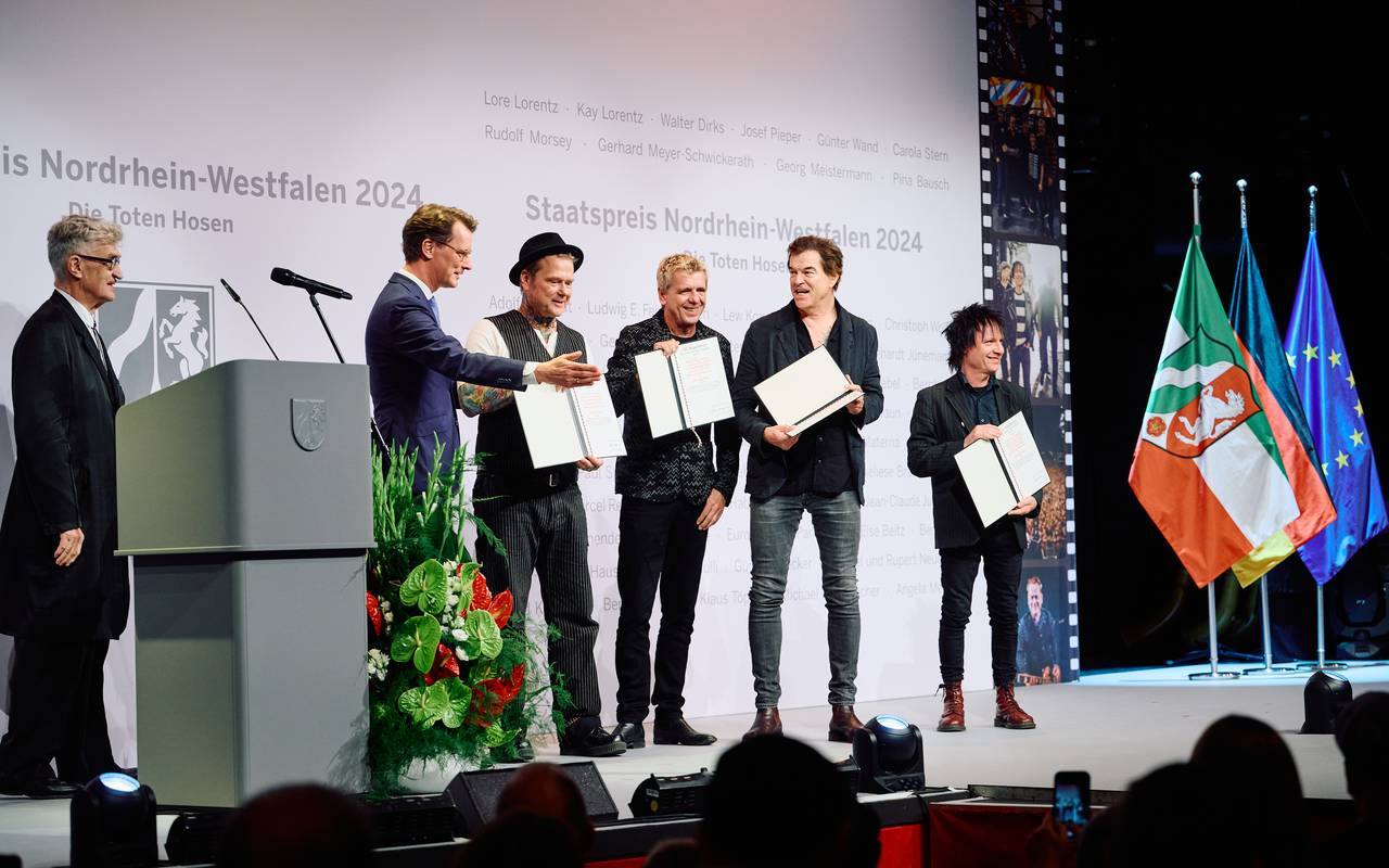 NRW-Ministerpräsident Hendrik Wüst verleiht den Toten Hosen den NRW-Staatspreis. Auch der Regisseur Wim Wenders ist auf der Bühne. Er hat die Laudatio gehalten.