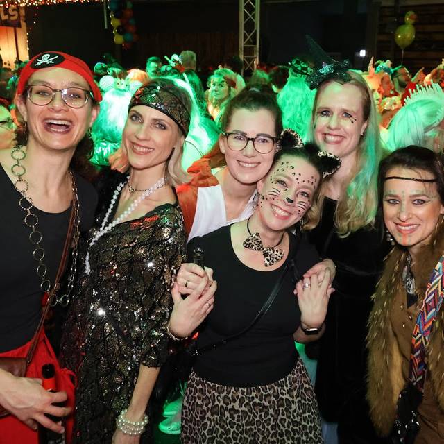 Ausgelassene Stimmung bei einer Altweiber-Party. Die Gruppe ist vergnügt und lächelt verkleidet in die Kamera.