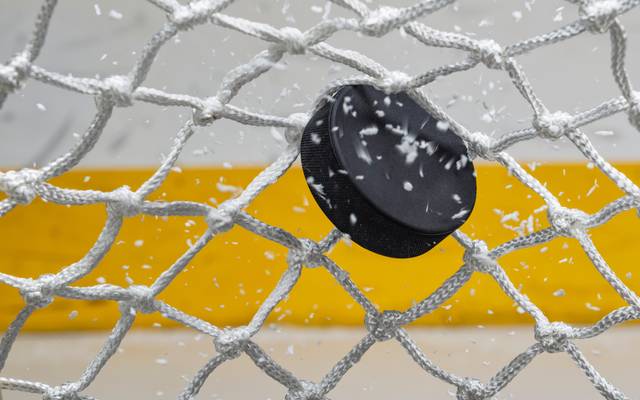 Ein Eishockey-Puck zappelt im Netz eines Eishockey-Tores.
