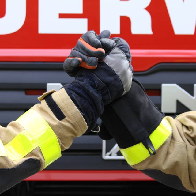 Zwei Feuerwehrleute machen einen Handshake.