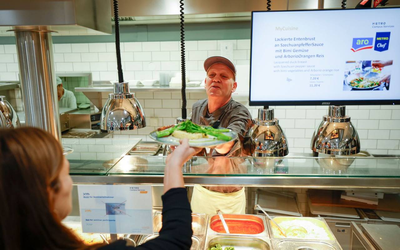 Ein Teilnehmer des "Housing First meets Gastro" Projekts gibt Essen in der Kantine aus
