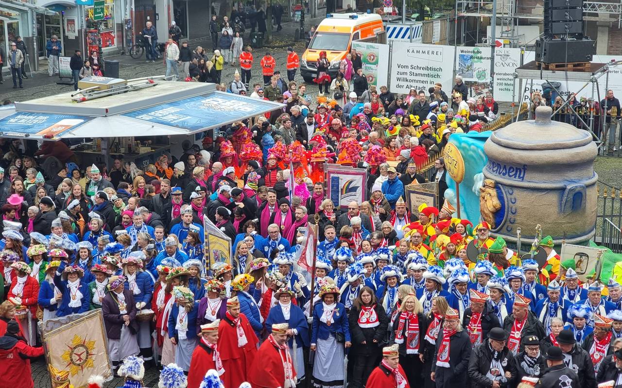 Karnevalisten aus Düsseldorf warten gespannt auf dem Hoppeditz. Er steckt noch im Senftopf, der auf dem Marktplatz steht.