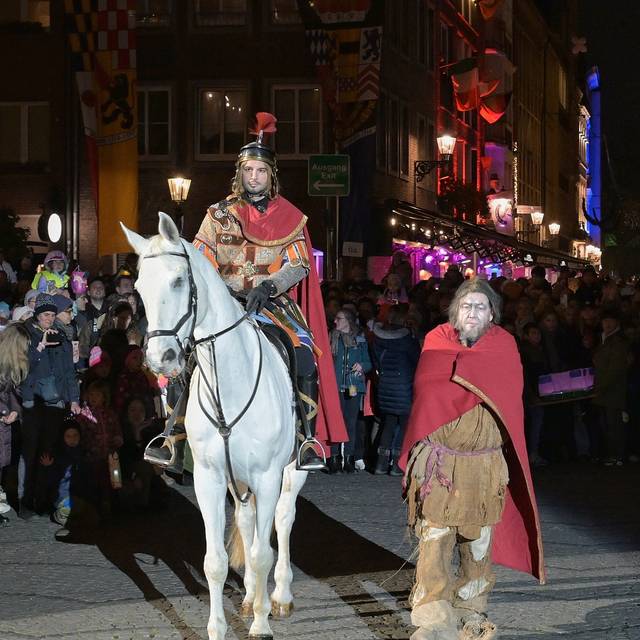 St. Martin hat seinen Mantel mit einem armen Mann geteilt. Der Marktplatz ist voller Menschen.