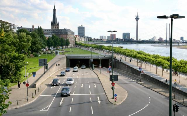 Der Rheinufertunnel und Autos. Hinter der Ausfahrt in Richtung Norden ist St. Lambertus, der Rheinturm und der Rhein erkennbar.