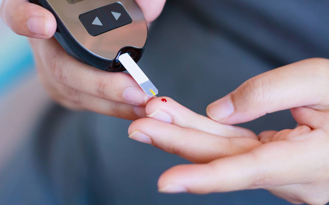 Diabetes-Test - eine Person hat sich gerade gepikst und misst den Zuckerspiegel.