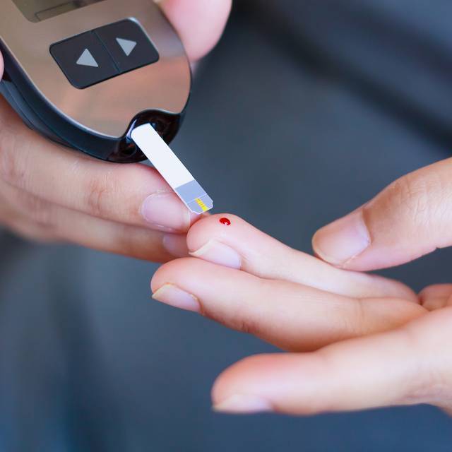 Diabetes-Test - eine Person hat sich gerade gepikst und misst den Zuckerspiegel.