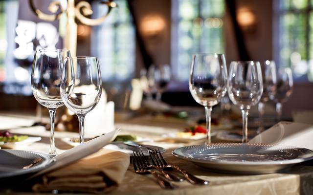 Ein gedeckter Tisch in einem Restaurant. Mit Glästern, Tellern und Besteck.