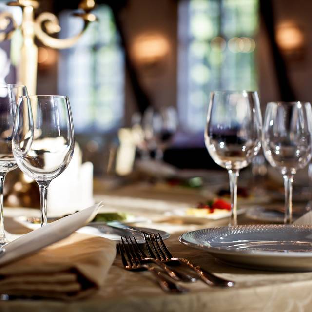 Ein gedeckter Tisch in einem Restaurant. Mit Glästern, Tellern und Besteck.