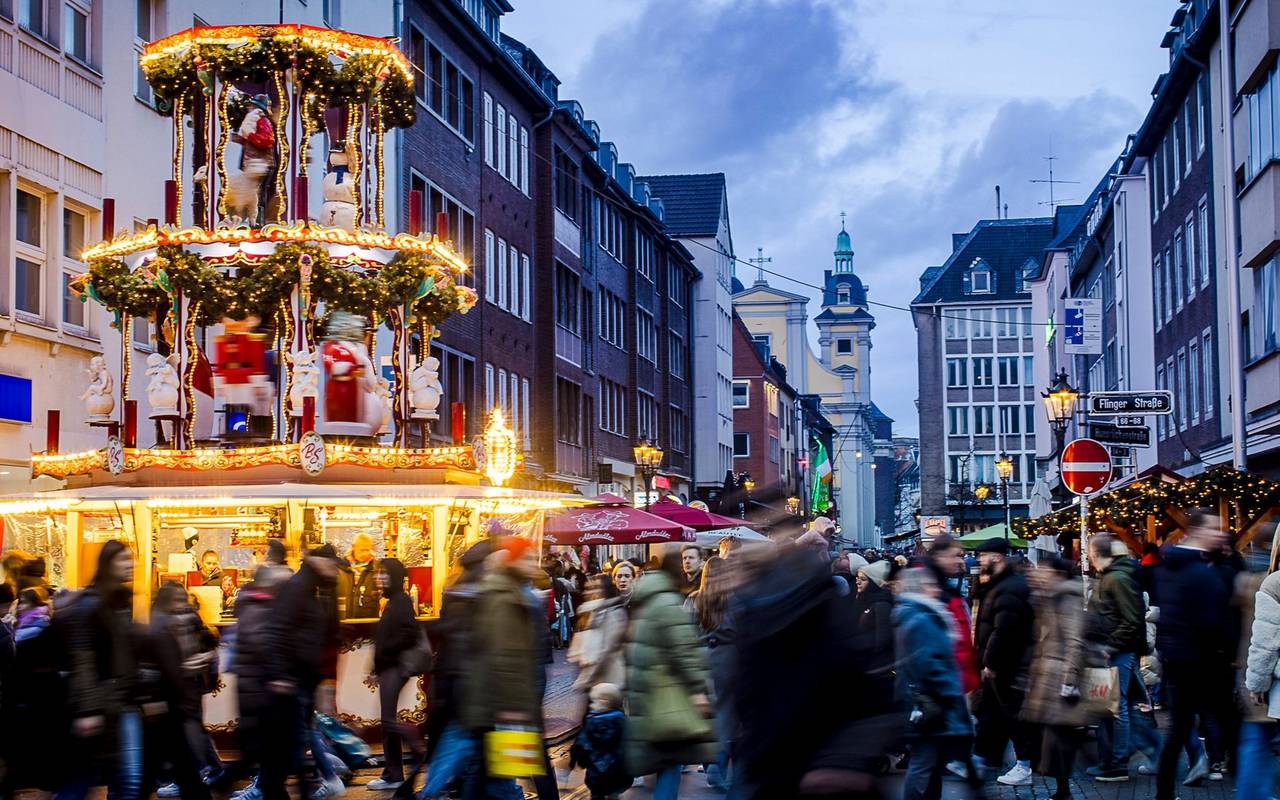 Weihnachtsmärke Überblick: Weihnachtsmarkt auf der Flingerstraße in der Altstadt. Viele Menschen sind unterwegs. Im Hintergrund ist die Andreaskirche erkennbar.