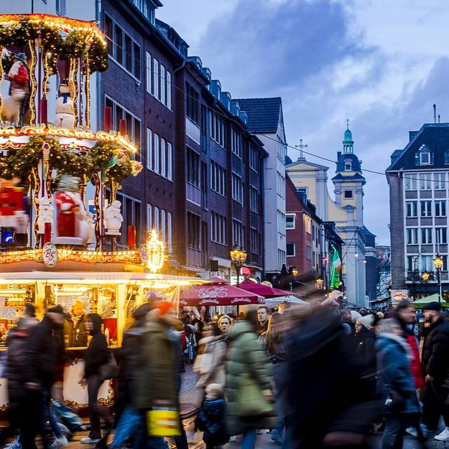 Weihnachtsmärke Überblick: Weihnachtsmarkt auf der Flingerstraße in der Altstadt. Viele Menschen sind unterwegs. Im Hintergrund ist die Andreaskirche erkennbar.
