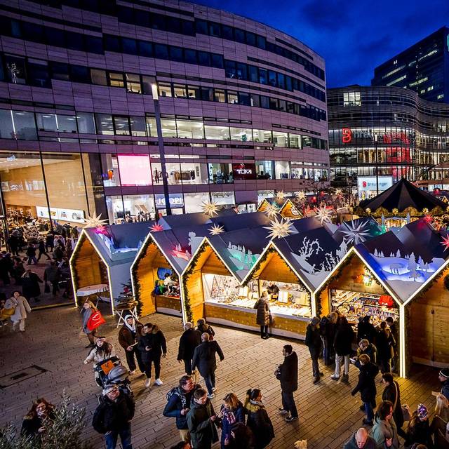 Weihnachtsmärke Überblick: Der Weihnachtsmarkt auf dem Schadowplatz. Mit vielen bunten Buden. Im Hintergrund ist der Kö-Bogen II zu erkennen.
