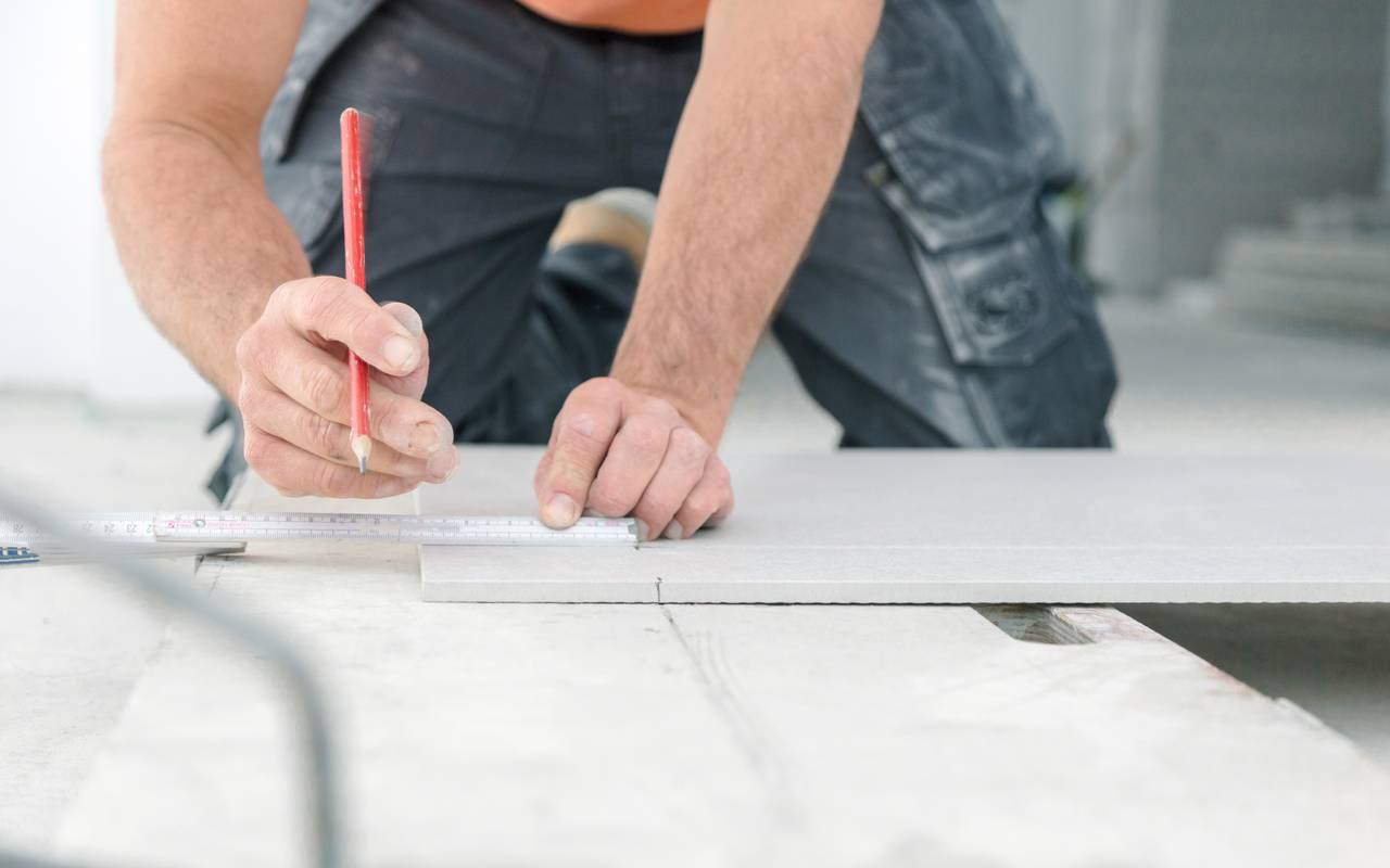 Ein Handwerker nimmt auf einer Arbeitsfläche mit einem Zollstock Maß.