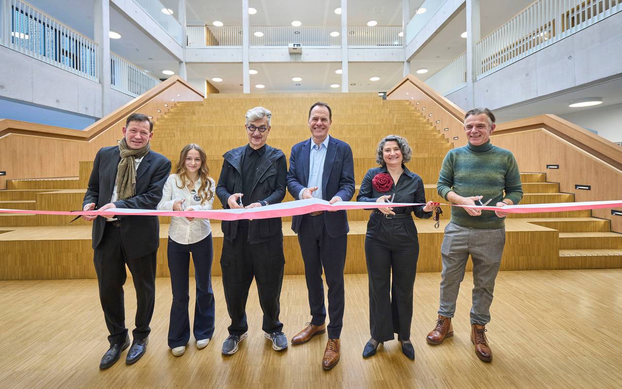 Wim Wenders zerschneidet zur Einweihung des Wim-Wenders-Gymnasiums feierlich ein Band. Auch Oberbürgermeister Stephan Keller legt Hand an.