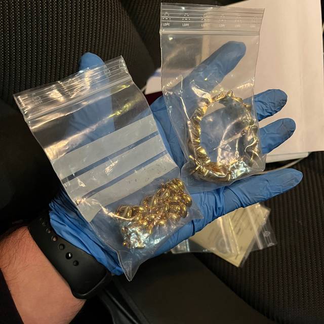 Diebesgut nach Wohnungseinbruch. Zu sehen ist eine Hand, die eine Kette und Schmuck in Plastiktüten präsentiert..