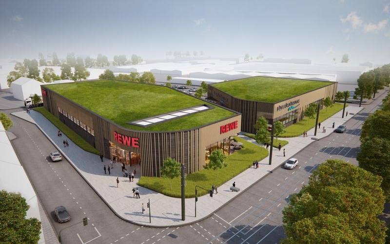So sollen der neue REWE und das neue Hallenbad an der Ulmenstraße einmal aussehen. Für das Bad rechnet Bezirksbürgermeisterin Schentek mit einer Eröffnung frühestens Ende 2028.