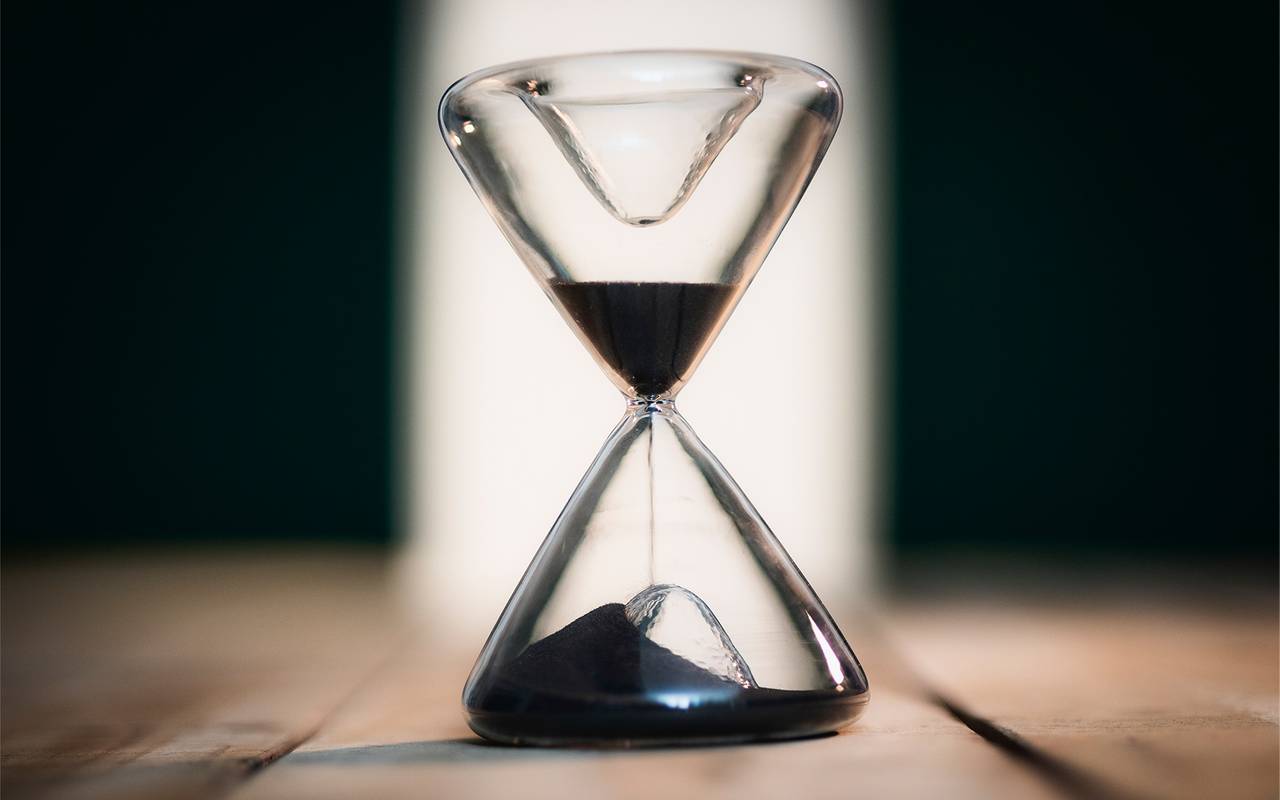 Eine Sanduhr symbolisiert Zeitarbeit und befristete Jobs und Arbeitsverträge.