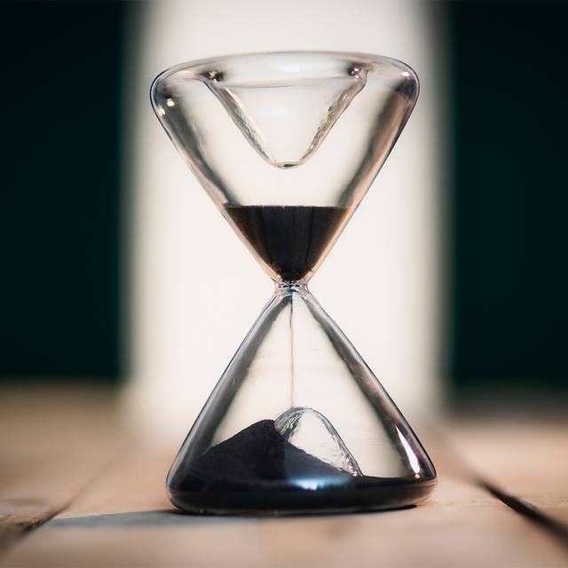 Eine Sanduhr symbolisiert Zeitarbeit und befristete Jobs und Arbeitsverträge.