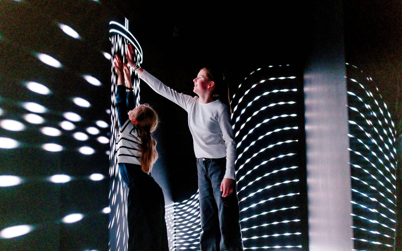 Zwei Kinder stehen im Kinderraum mit einer besonderen Lichtinstallation im Düsseldorfer Kunstpalast. Beide Kinder strecken sich und fassen eine Wand an.