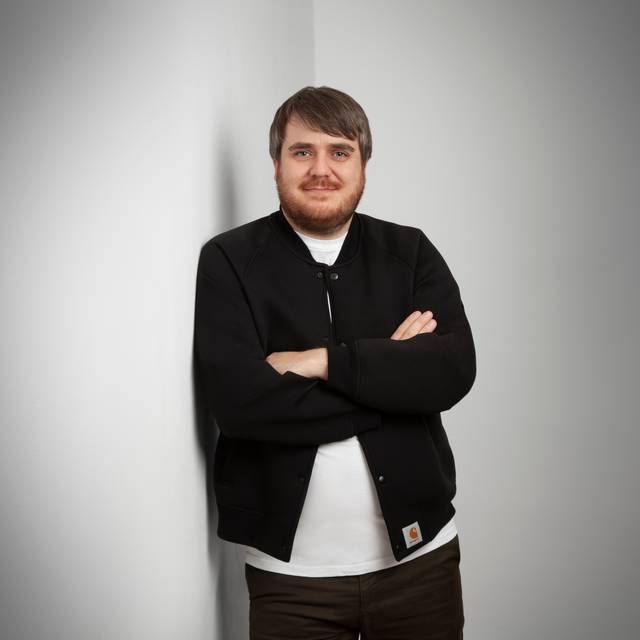 Der neue Gastro-Beauftragte der Stadt DüsseldorfJörn Topel posiert vor einer weißen Wand. Er trägt eine schwarze Hemd-Jacke und ein weißes T-Shirt und hat die Arme verschränkt