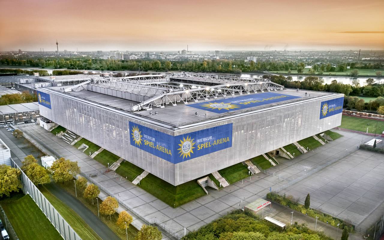 Die Merkur-Spiel-Arena im Vordergrund vor der Düsseldorfer Kulisse. Im Hintergrund sind unter anderem der Rhein und der Fernsehturm zu sehen.