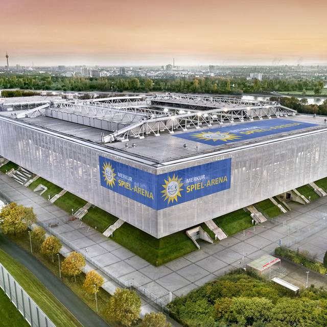 Die Merkur-Spiel-Arena im Vordergrund vor der Düsseldorfer Kulisse. Im Hintergrund sind unter anderem der Rhein und der Fernsehturm zu sehen.