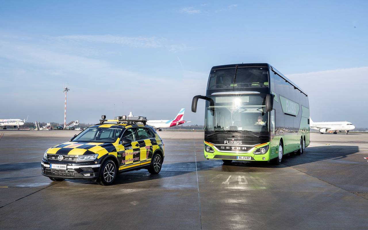Ein FlixBus am Düsseldorfer Flughafen hiner einem Follow Me-Fahrzeug