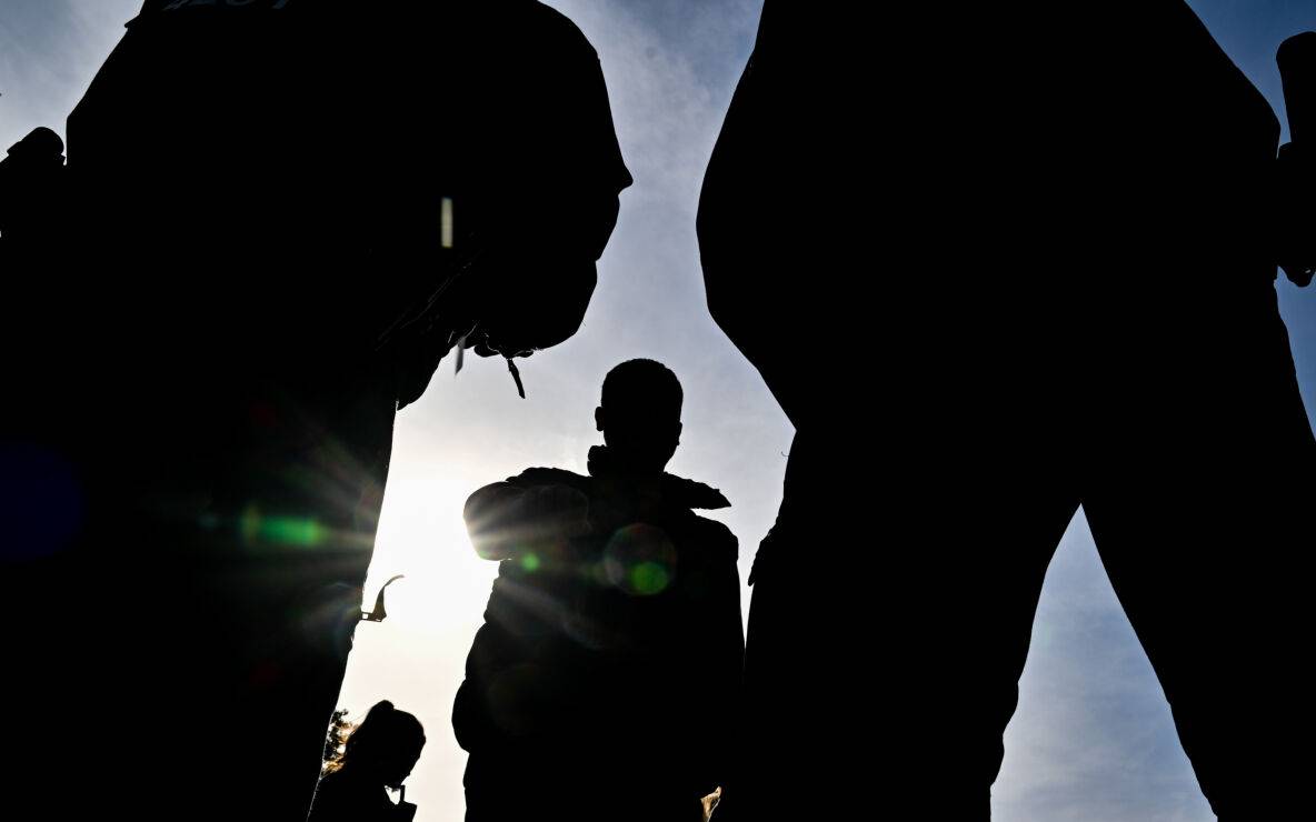 Beamten der Bundespolizei stehen vor einem unerlaubt eingereisten Migrant (M). der nahe Forst (Lausitz) aufgegriffen wurde