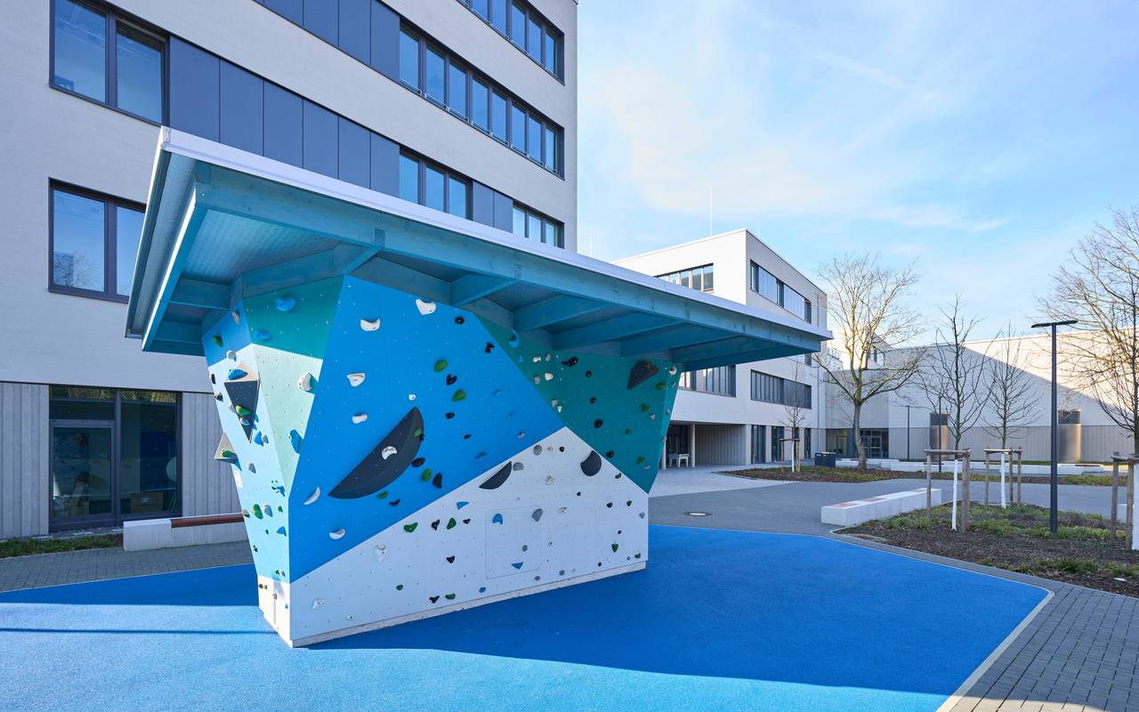 Schulhof vor den neuen Schulgebäuden an der Aldekerkstraße in Heerdt. Dort gibt es auch Bänke, Spiel-, Sport- und Klettergeräte.