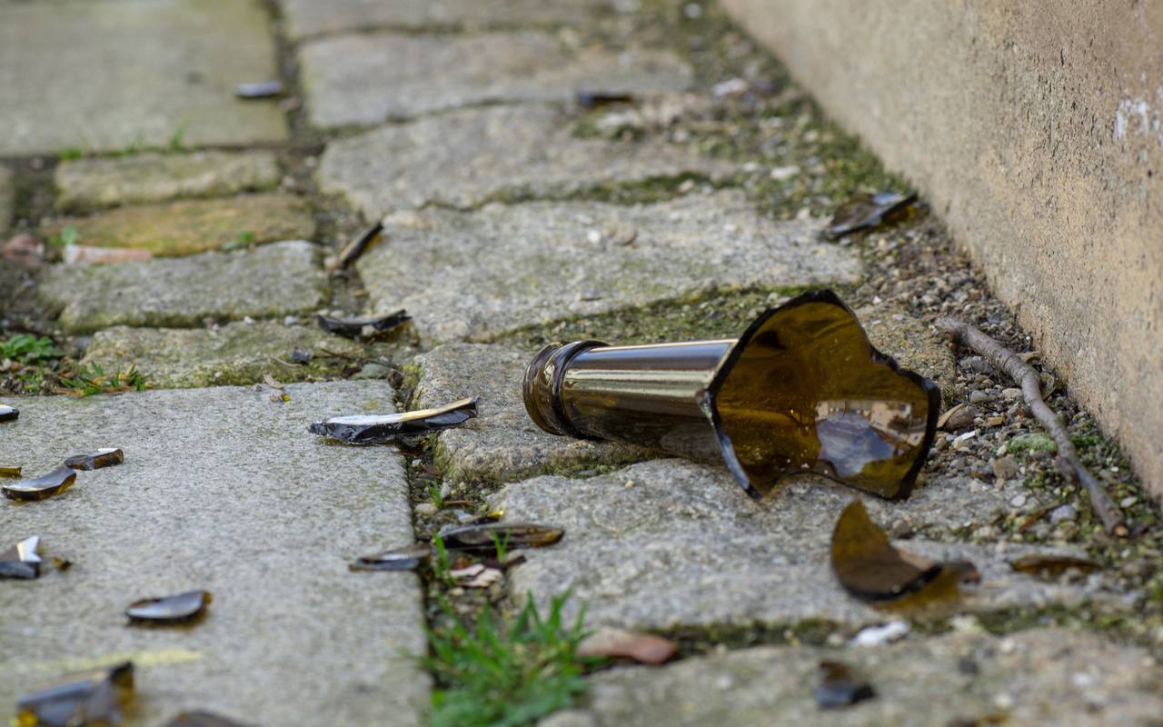 Eine zerbrochene Bierflasche liegt auf der Straße.