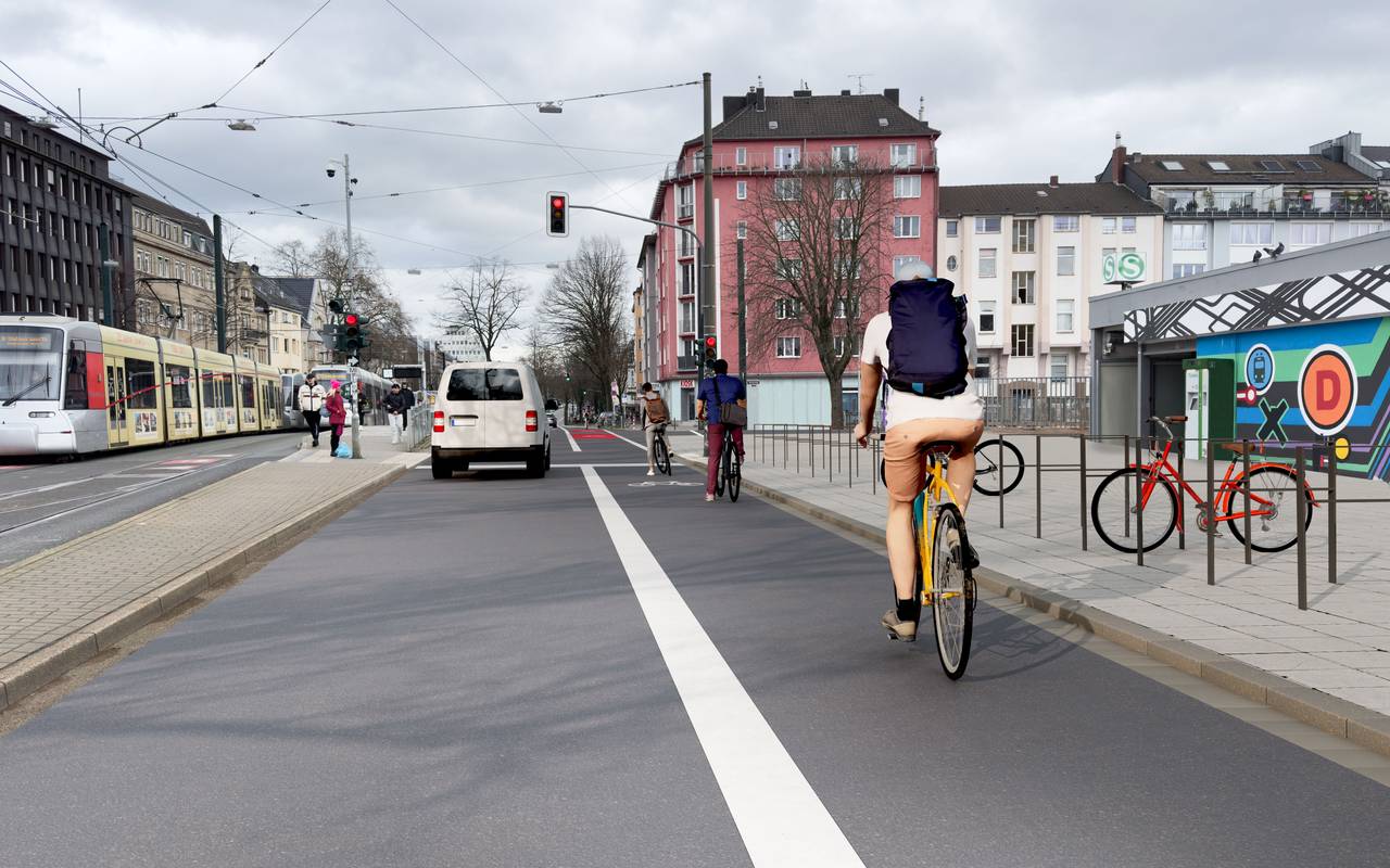 Über die Radleitroute am Wehrhahn fahren auf der rechten Spur Räder in Richtung Grafenberger Allee. Auf der linken Spur fahren Autos. Daneben befinden sich die Gleise für die Bahnen der Wehrhahnlinie.