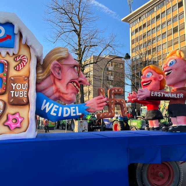 Mottowagen beim Karneval: Alice Weidel, die als Hexe Erstwählende in ihr Social-Media-Häuschen lockt.