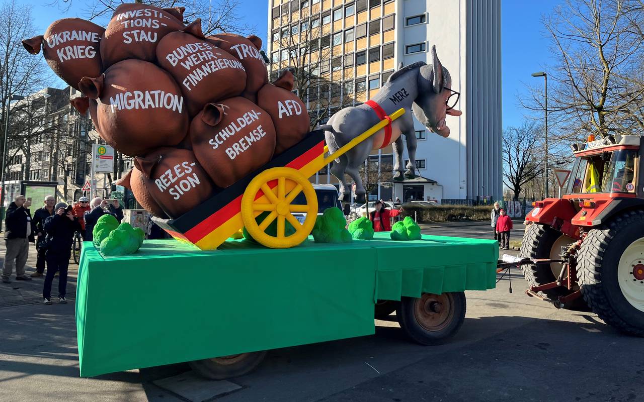 Mottowagen beim Karneval: Merz als Esel vor dem Deutschland-Karren  hängt in der Luft, Auf dem Karren liegen Säcke mit Aufschriften wie "AfD", "Migration" oder "Schuldenbremse"