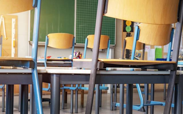 Leeres Klassenzimmer mit Stühlen auf den Tischen und leerer Tafel.