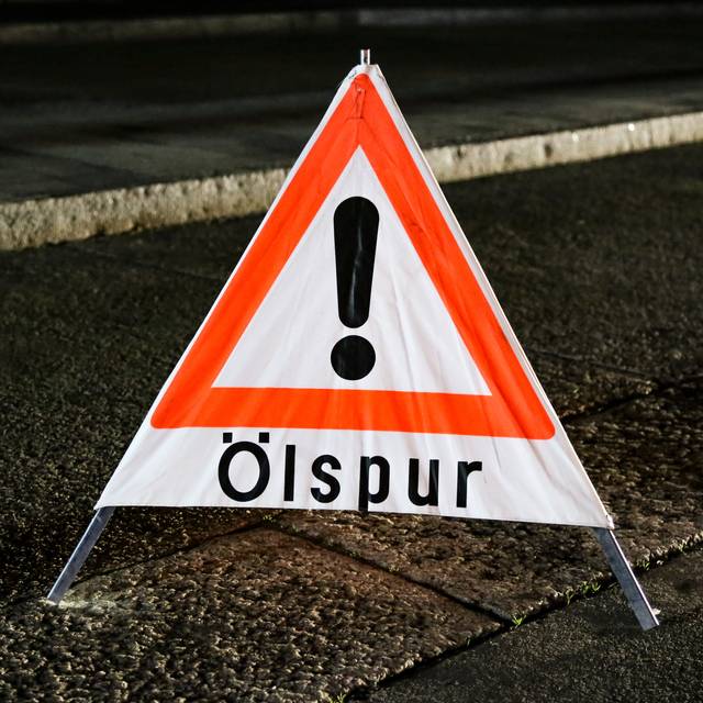 Ein Warnschild weist auf eine Ölspur hin.