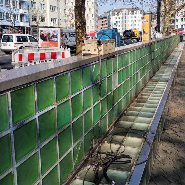 Die grünen Glasbausteine am Worringer Platz vor ihrer Beseitigung. Ein Stromkabel liegt auf der Glasbank. Im Hintergrund fließt der Verkehr.