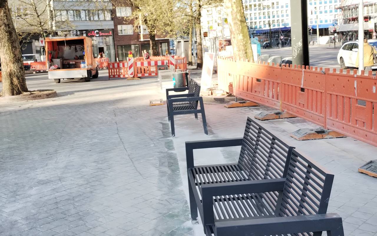 Neue, kleinere Bänke stehen auf dem Worringer Platz. Sie ersetzen die alten Glasbausteine. Im Hintergrund sind Baufahrzeuge zu sehen. Es laufen noch weitere Asphaltarbeiten.