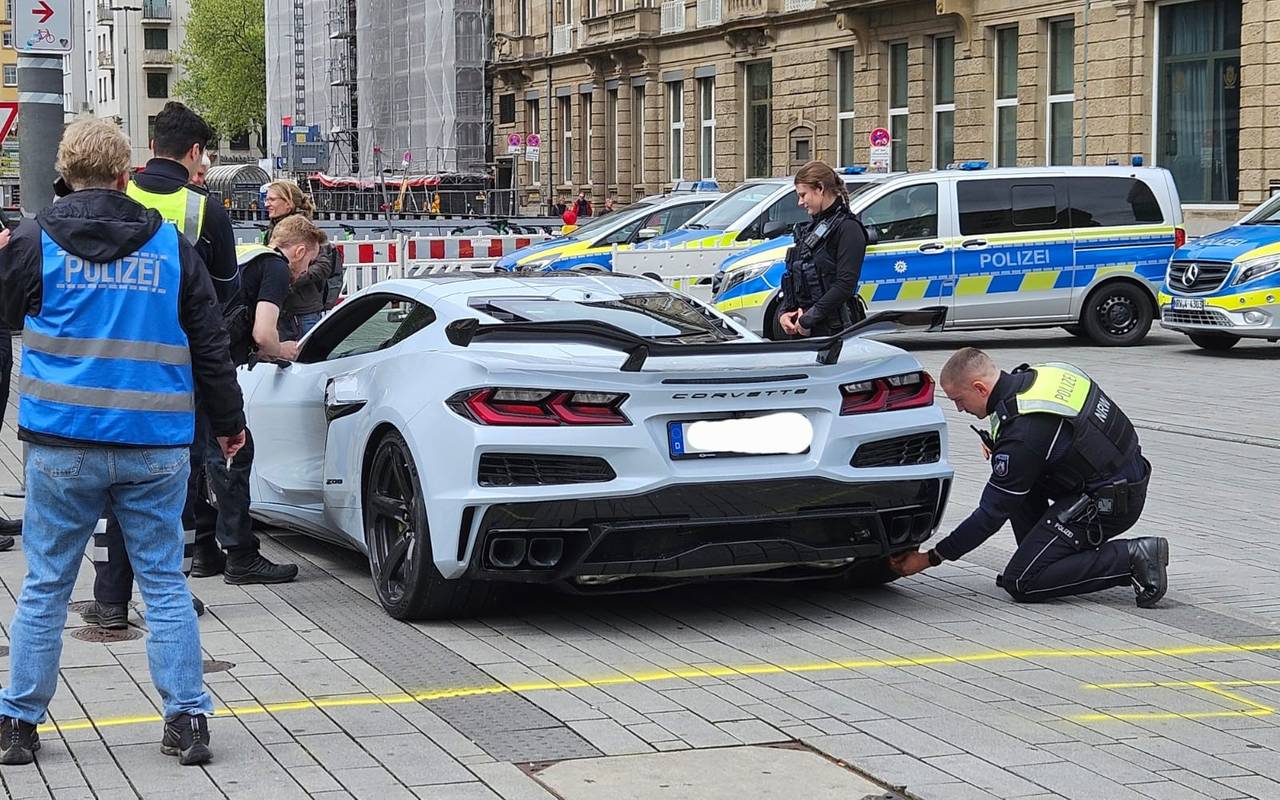 Mehrere Polizisten kontrollieren am Car-Freitag einen hellblauen Sportwagen.