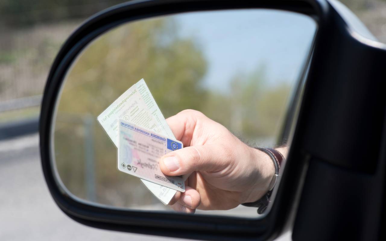 Ein Mann zeigt Führerschein und Fahrzeugschein bei einer Kontrolle der Polizei.