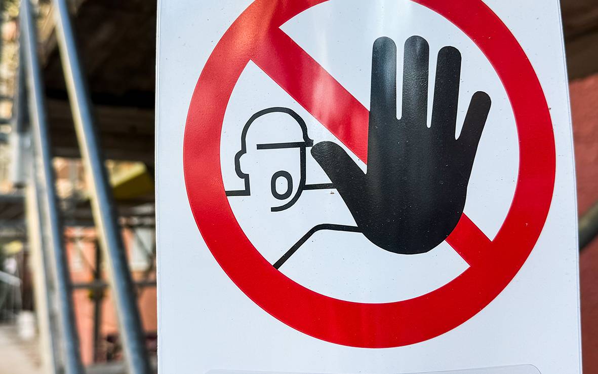 An einem Gerüst hängt ein Schild, auf dem ein durchgestrichener Roter Kreis, ein Mensch und der Schriftzug "Gerüst gesperrt" zu sehen sind.