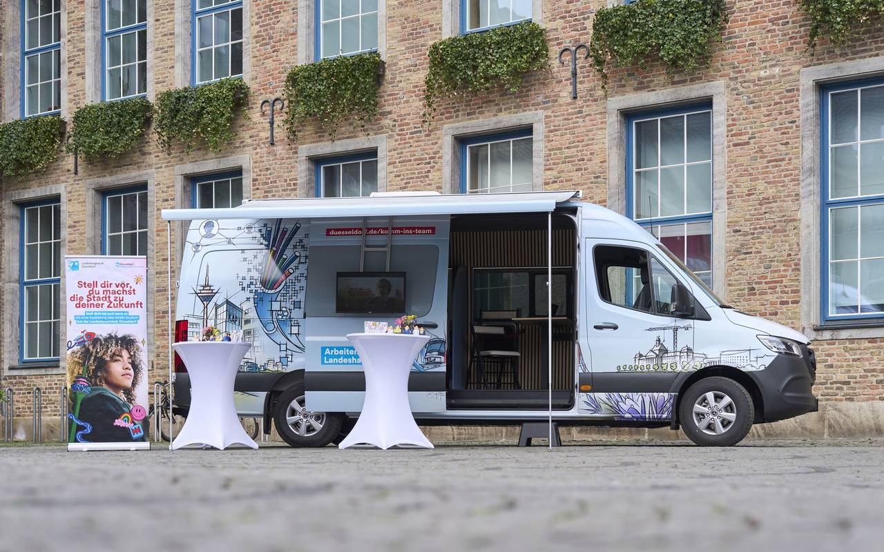 Der Karriere-Bus der Stadt steht vor dem Düsseldorfer Rathaus. Die Seitentüre ist geöffnet. Menschen können sich hier für einen Job bewerben.