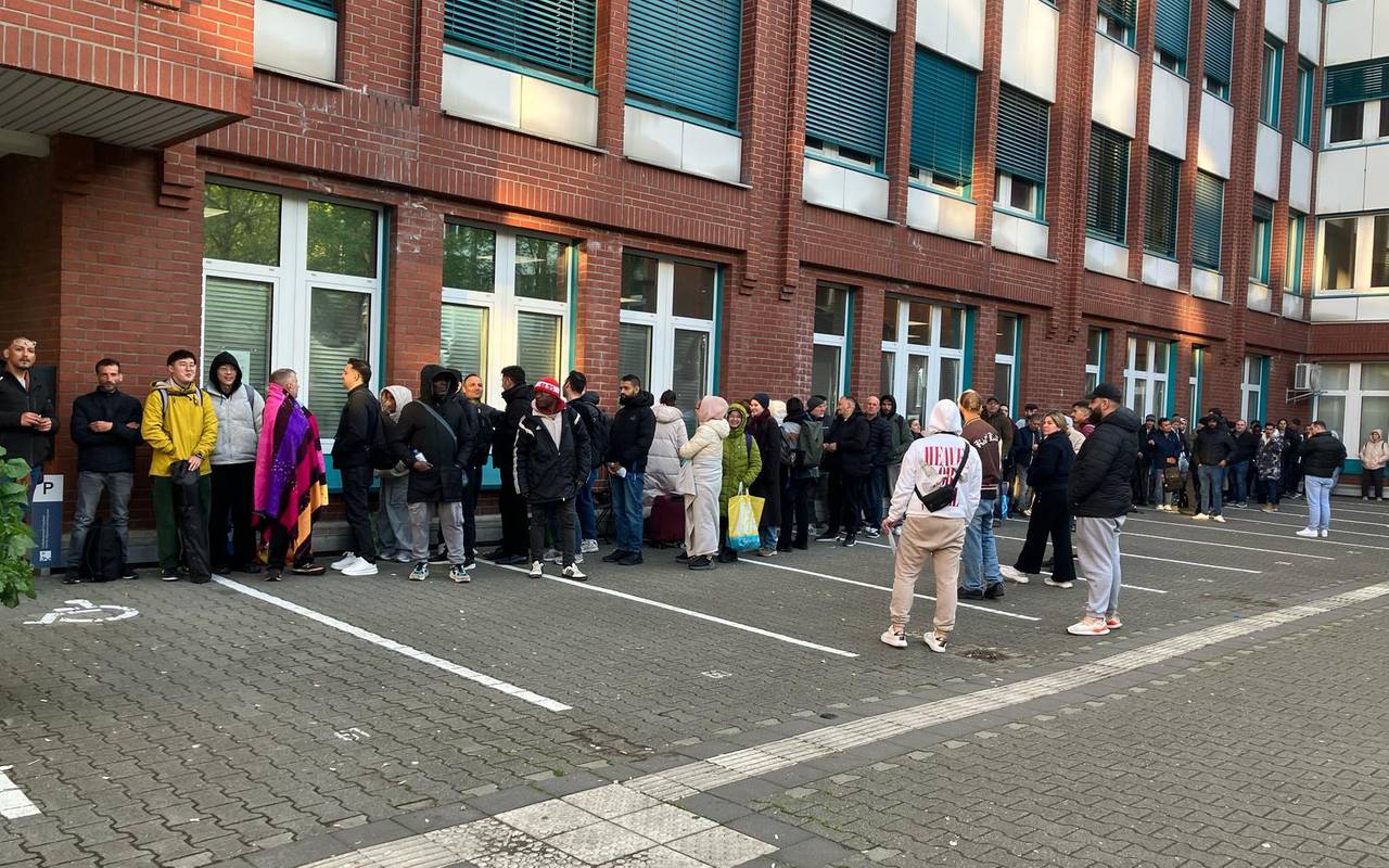 Menschen warten vor der Ausländerbehörde auf der Erkrather Straße.
