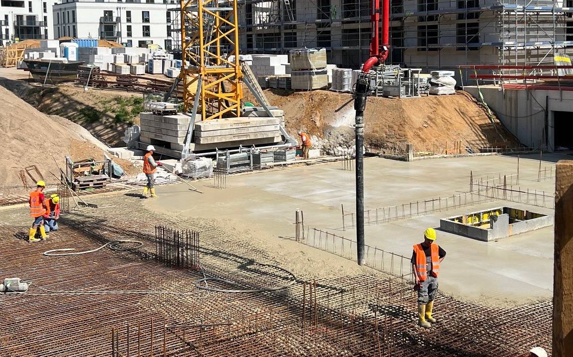 Die Bodenplatten des vierten Wohngebäudes der "Paulshöfe" in Düsseldorf-Benrath werden von Arbeitern gegossen.