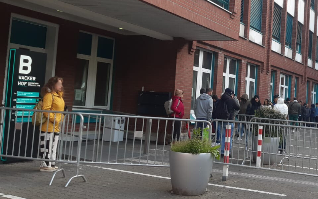 Menschen warten vor der Ausländerbehörde an der Erkrather Straße.