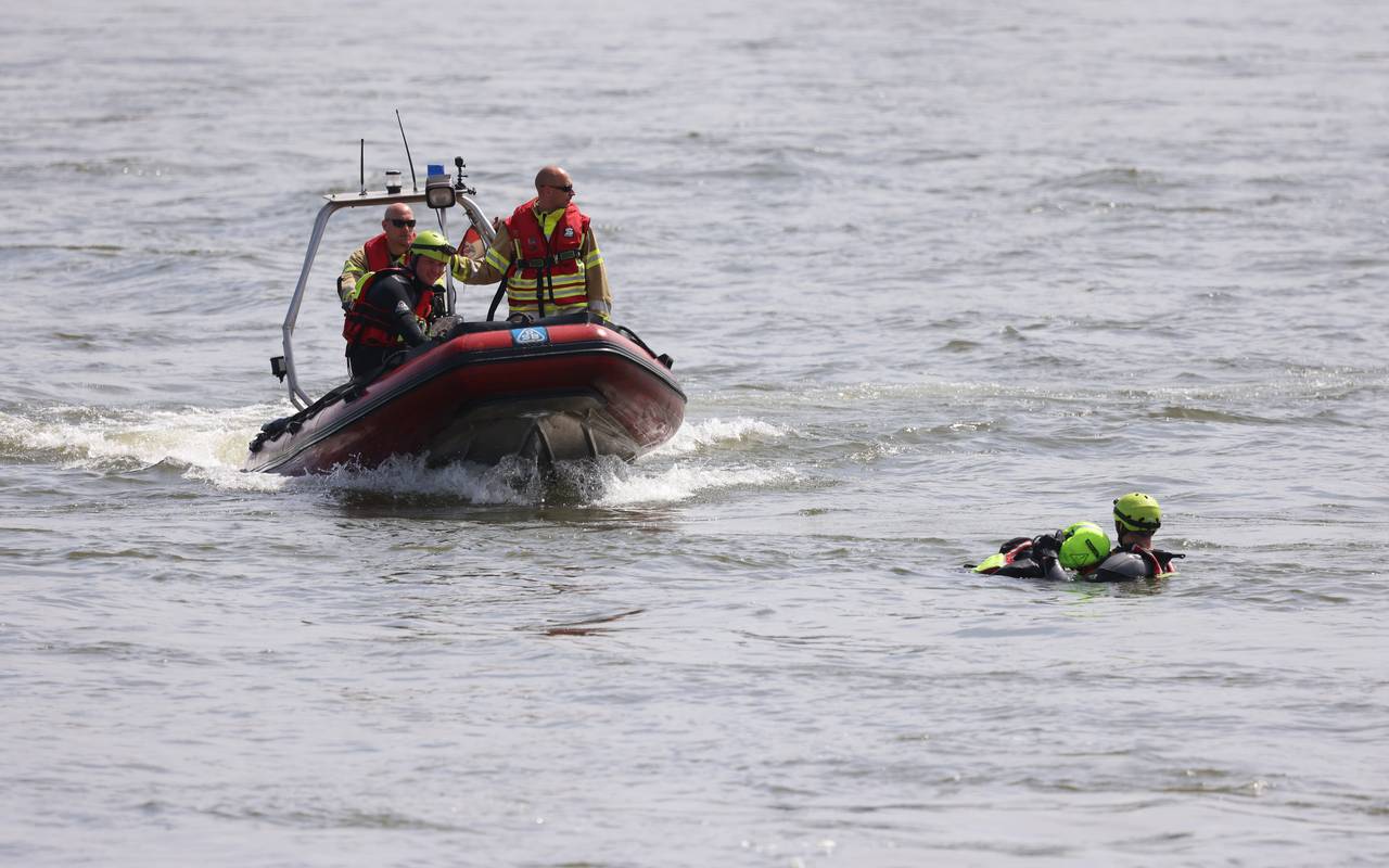 Feuerwehrboot mit Besatzung bei einer Übung auf dem Rhein. Im Wasser sind dabei ein Retter und eine zu rettende Person.