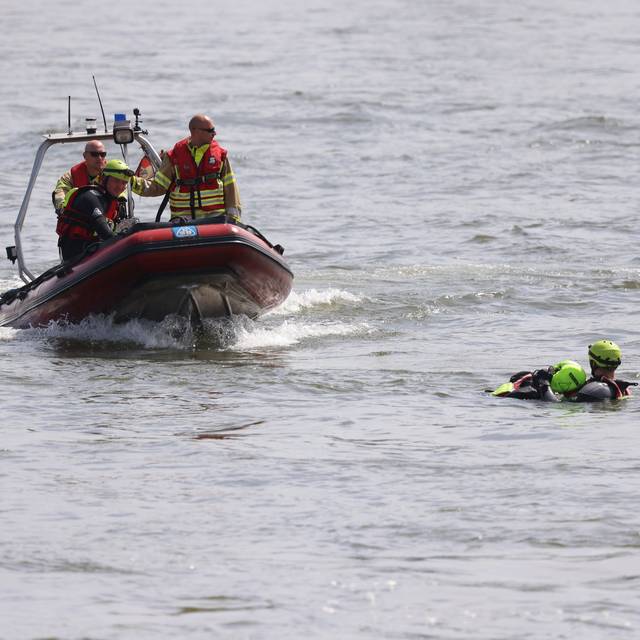 Feuerwehrboot mit Besatzung bei einer Übung auf dem Rhein. Im Wasser sind dabei ein Retter und eine zu rettende Person.