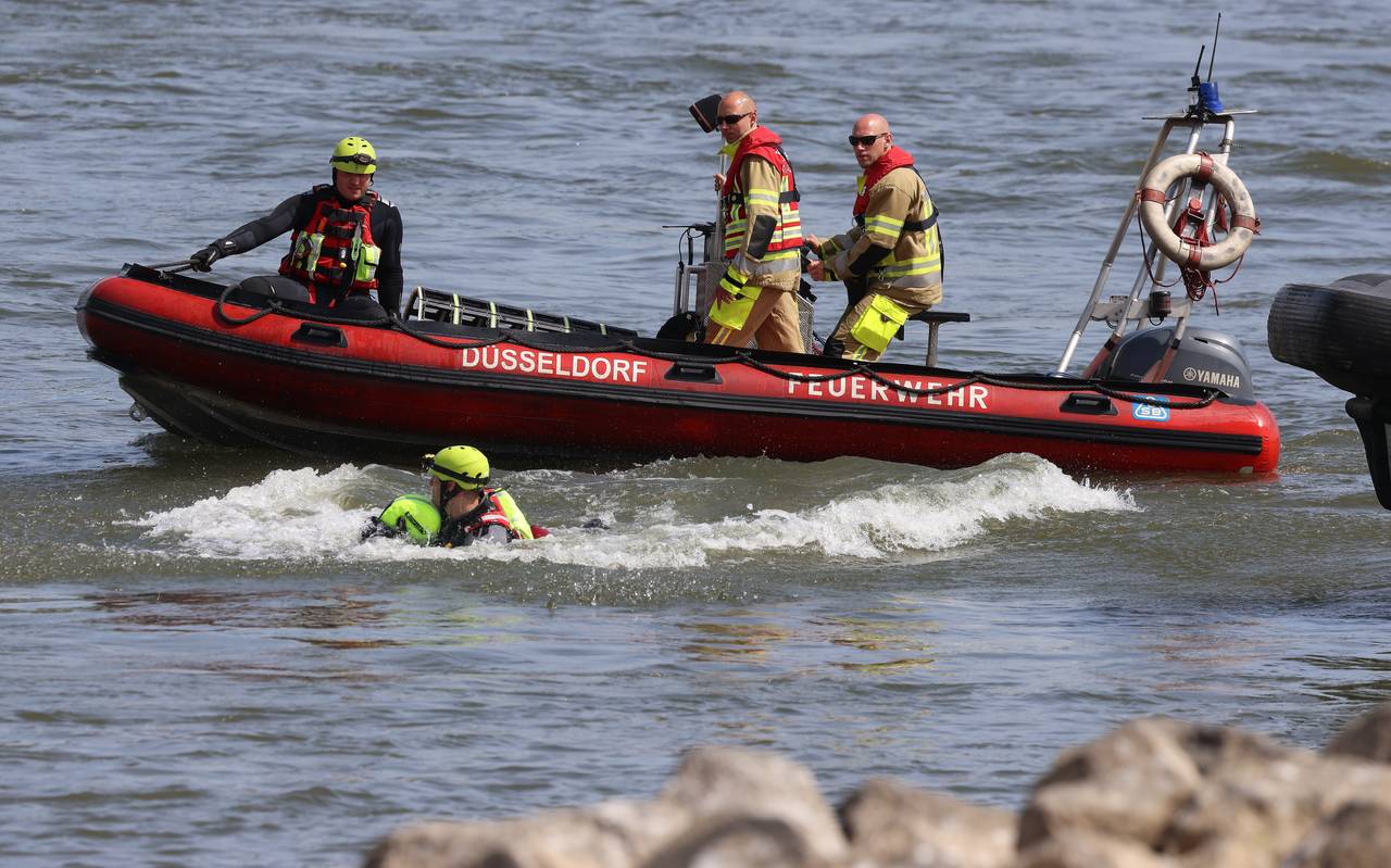 Feuerwehrboot mit Besatzung bei einer Übung auf dem Rhein. Im Wasser sind dabei ein Retter und eine zu rettende Person.