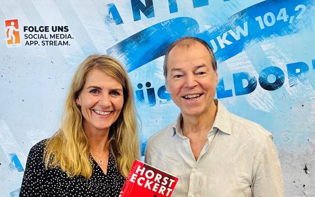 Moderatorin Claudia Monréal mit ihrem Talkgast Horst Eckert vor der Social Media Wand von Antenne Düsseldorf