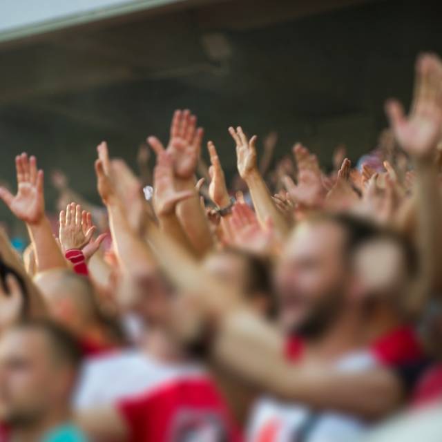 Fußballfans klatschen auf der Tribüne des Stadions.