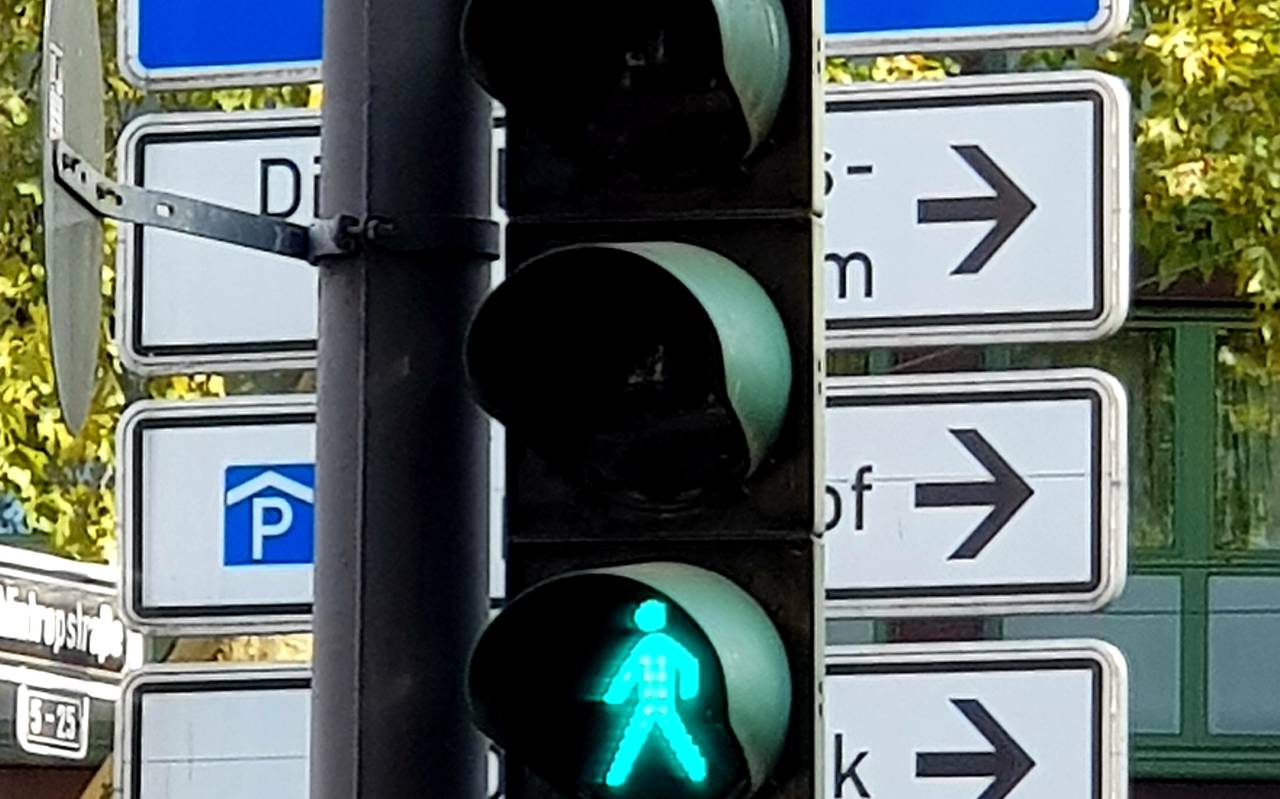 Eine normale Ampel leuchtet grün. Im Hintergrund sind mehrere Schilder zu sehen.
